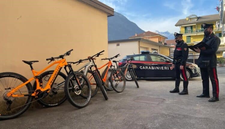 I Carabinieri del Nucleo Investigativo del Comando Provinciale di Verbania, in collaborazione con quelli della Stazione e del Nucleo Operativo e Radiomobile di Domodossola, hanno deferito in stato di libertà B.G., 46enne residente a Domodossola, per il furto di diverse biciclette elettriche “E-Bike”, avvenuto la notte tra il 16 e 17 marzo a Domodossola ai danni di un negozio specializzato nella vendita e assistenza di biciclette. Le indagini avviate a seguito del furto hanno permesso di raccogliere alcuni importanti indizi in ordine alla tecnica usata dal malfattore, parzialmente travisato da una felpa scura con cappuccio che, immortalato anche da alcune immagini di telecamere di videosorveglianza comunali, fornite dalla Polizia Locale di Domodossola, era stato ripreso effettuare diversi passaggi sulla strada, a pochi metri dal negozio, dapprima a piedi in avvicinamento all’esercizio commerciale e successivamente in allontanamento dallo stesso a bordo di bici ogni volta diverse. I Carabinieri, analizzando anche gli intervalli di tempo tra un viaggio e l’altro del ladro, hanno capito che si trattava sicuramente di una persona del posto, abitante in un raggio di non più di uno o due chilometri dal negozio. È Iniziato cosi uno screening dei possibili sospettati che rispondessero alle caratteristiche individuate dagli investigatori. Uno soggetto, in particolare, ha attirato l’attenzione dei carabinieri, poiché residente poco distante dal negozio, gravato da altri precedenti per furto, inoltre alcune caratteristiche quali età e misure antropometriche simili all’individuo ripreso dalle telecamere hanno fatto pensare potesse trattarsi proprio di lui. Un altro particolare importante è stata la segnalazione giunta ai Carabinieri che pochi giorni dopo il furto il sospettato era stato visto per le vie di Domodossola a bordo di una costosa bici elettrica. I Carabinieri quindi, dopo alcuni servizi anche notturni di appostamento nei pressi della sua abitazione e raccolti ulteriori elementi, la scorsa mattina hanno deciso di appurare se all’interno della sua abitazione o sue pertinenze potesse effettivamente trovarsi la refurtiva. Così, avuto accesso alle immediate pertinenze della cantina in uso al sospettato, trattandosi di un complesso di edilizia comunale, da una parziale visione del suo interno da uno spioncino, i militari hanno avuto conferma dei sospetti. A questo punto rintracciato l’uomo è stata eseguita una perquisizione in sua presenza sia alla cantina che nell’abitazione, rinvenendo 4 biciclette elettriche del tipo “e-bike” di varie marche e ben 7 “caribatteria” specifici per la ricarica di quest’ultime, il tutto per un valore complessivo di decine di migliaia di euro. Sono stati inoltre rinvenuti e sequestrati i capi di abbigliamento utilizzati la notte del furto e ripresi dalle telecamere, in particolare la felpa con cappuccio riportante una vistosa scritta nella parte anteriore. L’uomo, pertanto, è stato denunciato per furto aggravato e la refurtiva rinvenuta restituita al legittimo proprietario. Dall’esame conclusivo della vicenda risulta inoltre che il denunciato, qualche giorno prima del furto, avrebbe fatto anche un sopralluogo nel negozio, in orario di apertura, chiedendo agli addetti alle vendite informazioni sulle biciclette esposte, probabilmente per scegliere quelle ritenute di maggiore interesse, nonché familiarizzare con i locali del negozio stesso.